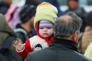 A migrant holding a child walks near the Turkey's Pazarkule border crossing with Greece's Kastanies, near Edirne, Turkey, March 4, 2020.