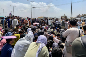 Afghan people gather along a road as they wait to board a U S military aircraft to leave the country, at a military airport in Kabul on August 20, 2021 days after Taliban's military takeover of Afghanistan. (Photo by Wakil KOHSAR / AFP)
