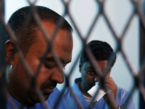 Defendants Abdulkarim Lalji (L) and Hani Ahmad Mohammad, convicted of spying for Iran, stand behind courtroom bars at a state security court of appeals in Sanaa March 25, 2013. The court on Monday commuted their death sentences to five years in prison. The pair were convicted in 2009 of providing the Iranian Embassy in Yemen with military information, according to the Yemen News Agency (SABA).  REUTERS/Khaled Abdullah