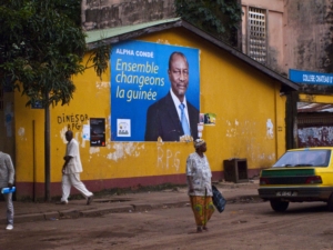 Pedestrians walk past a poster for Guinea presidential candidate Alpha Conde in Conakry, September 13, 2010. Police deployed extra forces around Guinea's capital Conakry on Monday after street fighting between supporters of rivals for its presidential election left one dead and 50 injured over the weekend. REUTERS/Joseph Penney (GUINEA - Tags: POLITICS ELECTIONS)