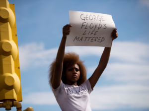MINNEAPOLIS, MN - MAY 26: A woman holds a sign stating "George Floyd's Life Mattered" during a protest outside the Cup Foods on May 26, 2020 in Minneapolis, Minnesota. Four Minneapolis police officers have been fired after a video taken by a bystander was posted on social media showing Floyd's neck being pinned to the ground by an officer as he repeatedly said, "I canâ€™t breathe". Floyd was later pronounced dead while in police custody after being transported to Hennepin County Medical Center.