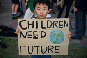 A child holds a placard during a 'drop dead' flashmob protest against climate change consequences at Lumpini Park in Bangkok, Thailand November 29, 2019. REUTERS/Chalinee Thirasupa