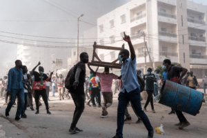 DAKAR - 9/02/2024 : des manifestants crient des slogans et ramassent des barils et des tables à brûler lors d'affrontements avec la police en marge d'une manifestation contre le report de dernière minute des élections présidentielles.  Le 8 février 2024, le parlement a soutenu la décision soudaine du président de reporter de 10 mois l'élection du 25 février, déclenchant une vive réaction de l'opposition et l'inquiétude de la communauté internationale. © GUY PETERSON / AFP