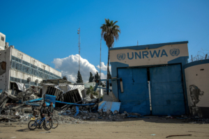(FILES) People walk past the damaged Gaza City headquarters of the United Nations Relief and Works Agency for Palestine Refugees (UNRWA) on February 15, 2024, amid ongoing battles between Israel and the militant group Hamas. Israel faced a mounting international backlash on October 29 after its parliament approved a bill banning the main UN aid agency for the devastated Gaza Strip. Despite objections from the United States and warnings from the UN Security Council, Israeli lawmakers overwhelmingly passed the bill banning the United Nations agency for Palestinian refugees, UNRWA, from working in Israel and annexed east Jerusalem.  © AFP
