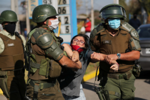 A woman is detained after shouting slogans against riot police at a poor neighborhood where people are protesting the lack of help from the government, during a general quarantine imposed due to a surge of fresh coronavirus disease (COVID-19) cases, at 'El Bosque' area in Santiago, Chile May 18, 2020. REUTERS/Ivan Alvarado