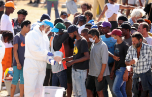 Homeless people queue for food at a camp set up by disaster management authorities during the 21-day nationwide lockdown aimed at limiting the spread of coronavirus disease (COVID-19) in Cape Town, South Africa, April 9, 2020.