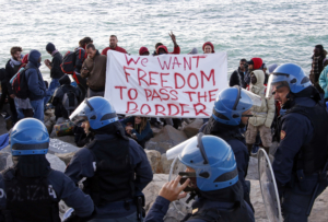 Migrants and activists hold a banner as they face off with Italian police on the seawall at the Saint Ludovic border crossing on the Mediterranean Sea between Ventimiglia, Italy and Menton, France, September 30, 2015. A migrant camp on the French- Italian border was dismantled Wednesday morning by about 150 Italian carabinieri and police officers. REUTERS/Eric Gaillard TPX IMAGES OF THE DAY