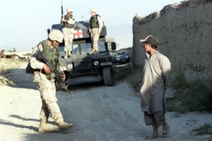 An Afghan boy watches U.S. soldiers at a check point near the site of a blast outside the U.S. headquarters at Bagram north of Kabul on October 3, 2003. At least four Afghans were killed and two were missing after the blast outside the main base of U.S. forces in Afghanistan, which a U.S. officer said may have been caused by children playing with bombs.