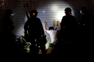 Men detained by riot police kneel by a wall after a protest at Yuen Long station against violence that happened two months ago when white-shirted men wielding pipes and clubs wounded both anti-government protesters and passers-by, in Hong Kong, China September 21, 2019. Picture taken September 21, 2019. REUTERS/Tyrone Siu