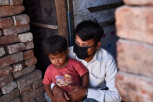 Un réfugié rohingya portant un masque protecteur se trouve à l'extérieur de son domicile temporaire alors que de la nourriture gratuite est distribuée par People for Social Development en collaboration avec la police de Delhi, le 15e jour de l'emprisonnement national de 21 jours pour freiner la propagation du coronavirus, à Okhla en avril. 8, 2020 à New Delhi, Inde.