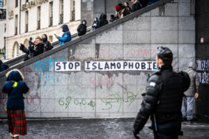 Un gendarme passe devant un collage avec le message "stop islamophobie" sur la place de la Bastille