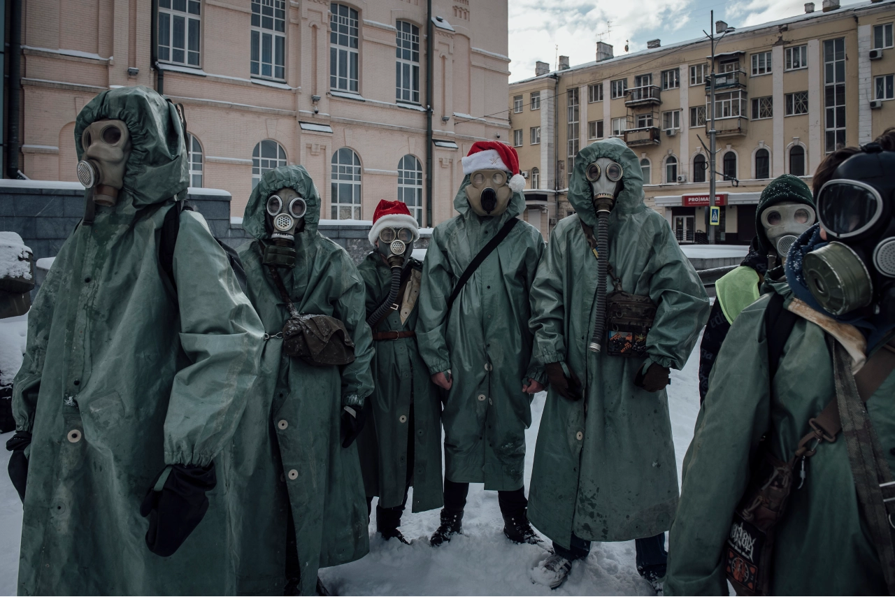 Sur la place de la Constitution, en plein centre-ville de Kharkiv, des adolescents s’amusent déguisés en combinaisons anti-radiations et masques à gaz datant de l’ère soviétique. Kharkiv, le 30 décembre 2025